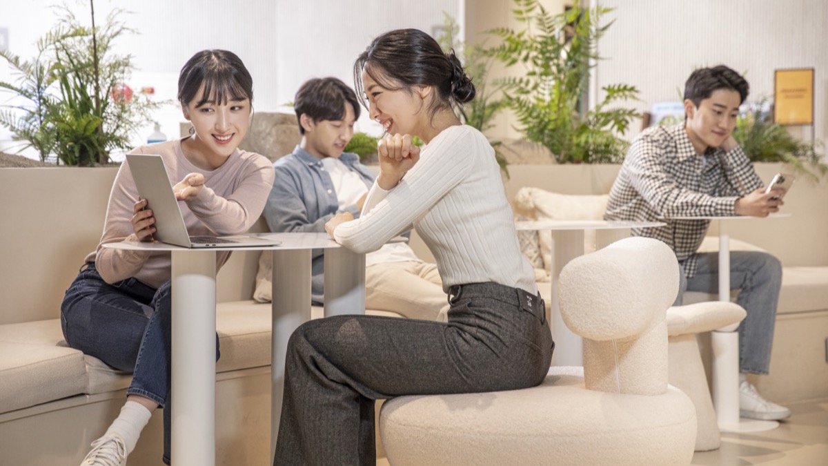 라운지에서 노트북과 스마트폰으로 정보를 찾아보는 사람들