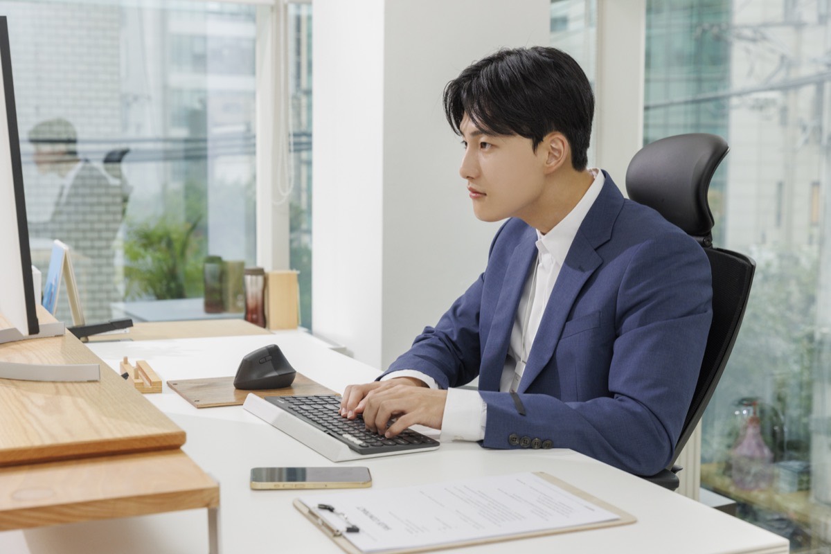 사무실 책상에서 컴퓨터로 서류 작업을 하는 남성