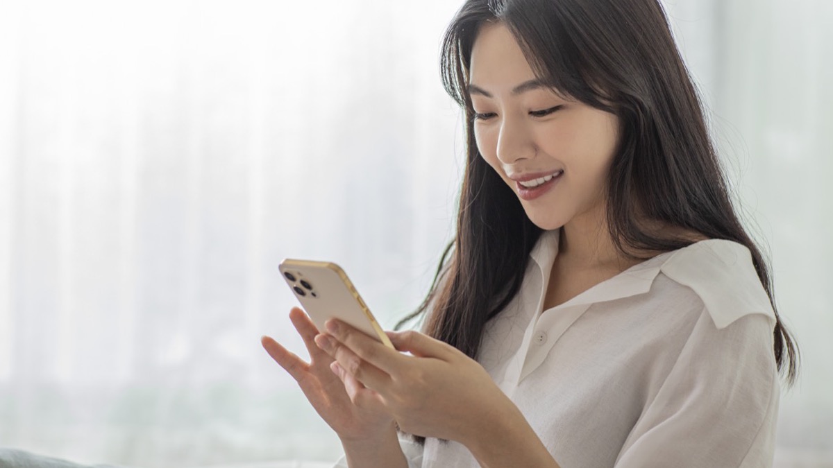 소파에 앉아 스마트폰으로 병원에서 온 안내 문자를 확인하는 여성